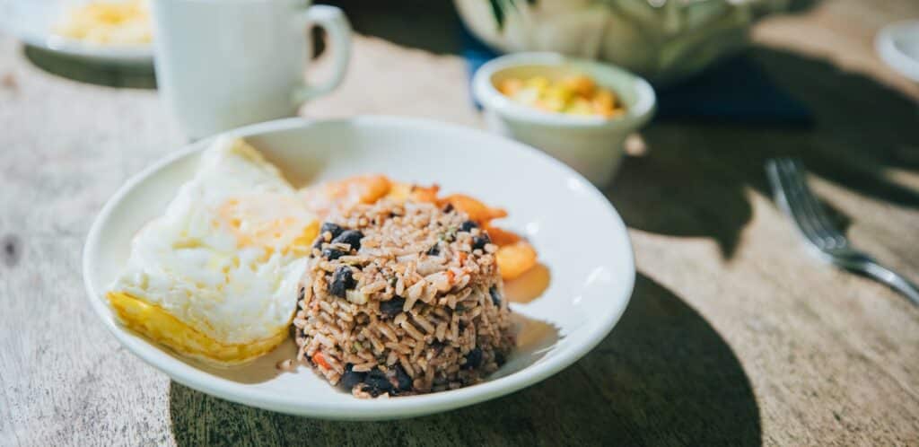 a plate of breakfast, gallo pinto, eggs, plantains, coffee