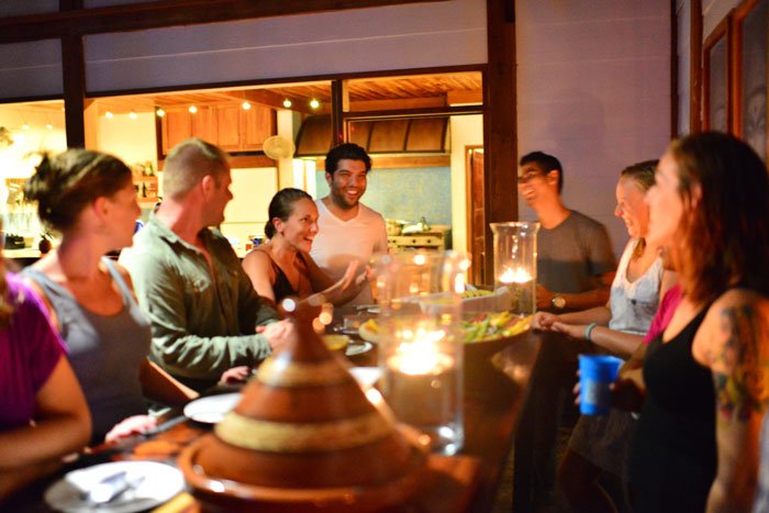 Group of people from a Blue Osa yoga retreat gathered around a large dining table in Blue Osa's dining room for a farm-to-table meal in Costa Rica. 