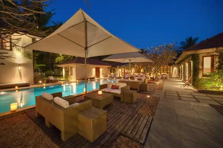 a courtyard with chairs, a pool and sun unbrellas
