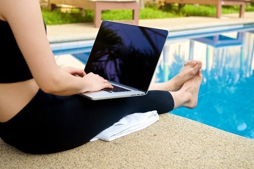 Girl work with laptop at pool on yoga vacation