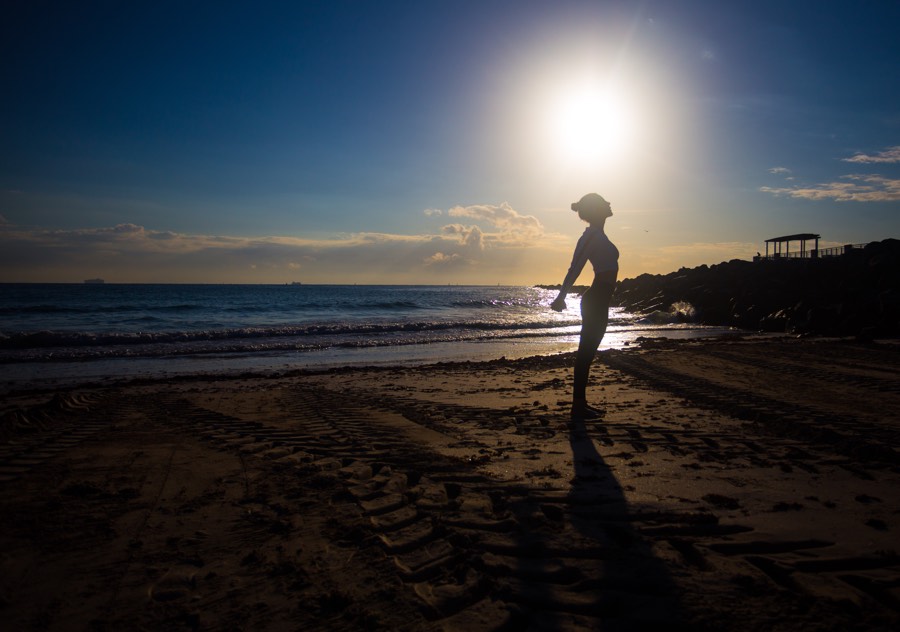 Silhouette of a woman on the beach stretching her arms behind her back in Costa Rica. 