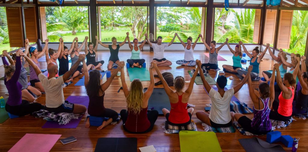 Yoga teacher training students celebrating together in seated meditation circle 300-hour YTT cohort Blue Osa