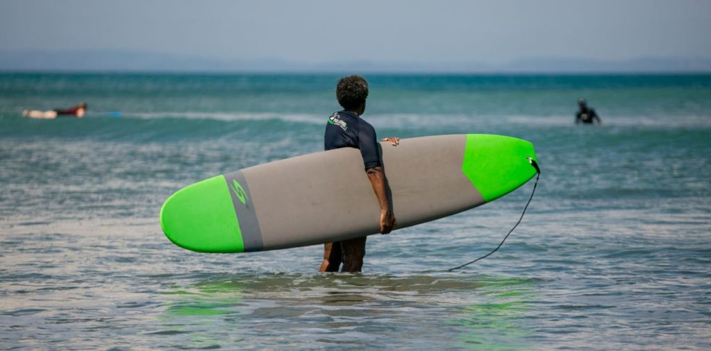 man hold a surfing board looking out to the sea