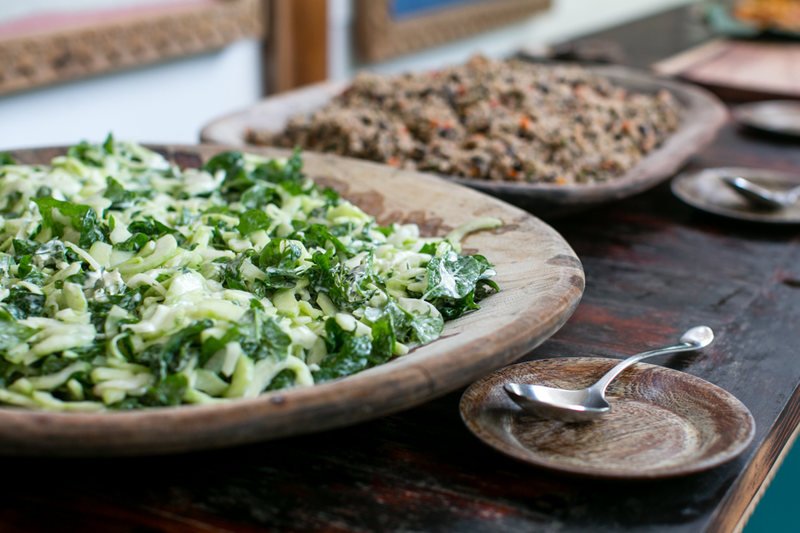 A buffet of a green salad and rice and beans in wooden dishes. 