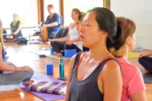 Yoga students sitting back to back practicing mantras in Blue Osa's yoga shala in Costa Rica. 