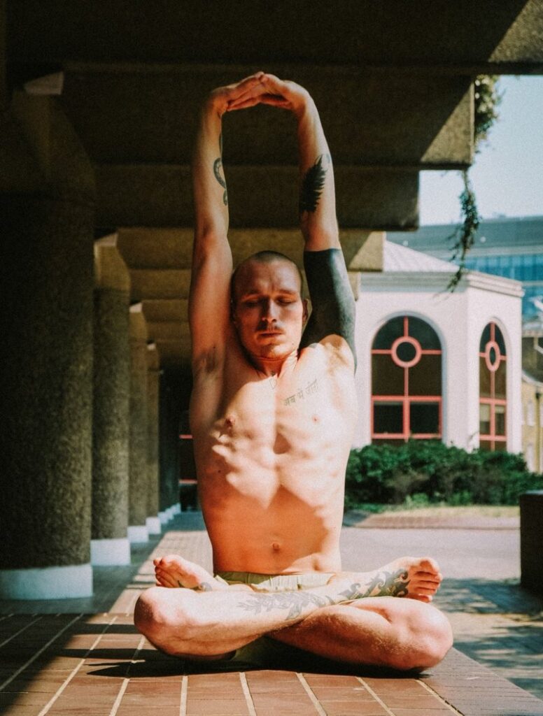 young man doing a yoga stretch in a seated lotus