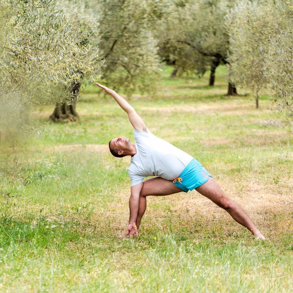 Yogi Aaron practicing twisted lunge pose in a field. 