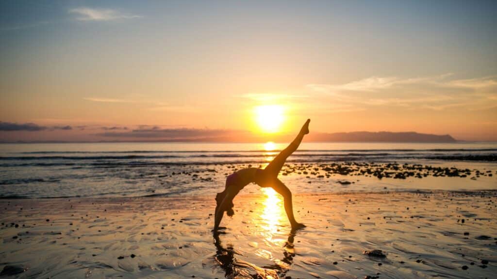 Woman doing a one legged back bend on the beach during sunset in Costa Rica.