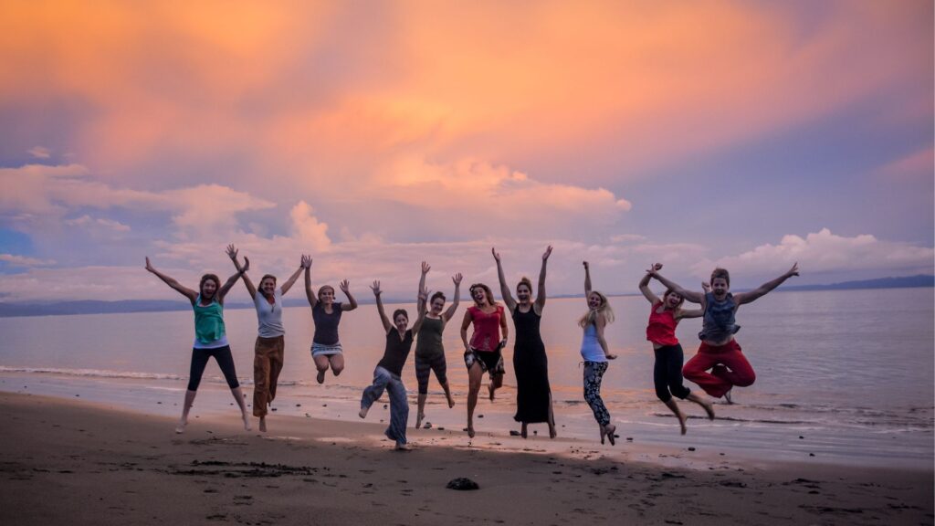 Yoga students jumping in the air on the beach at sunset in Costa Rica. 