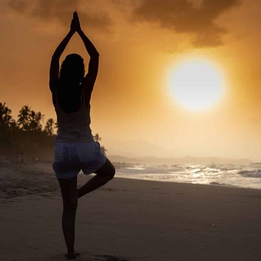 woman in white tank top and white shorts standing on beach during sunset