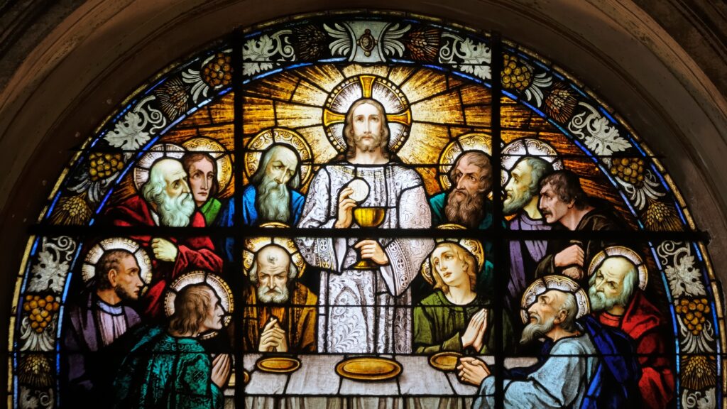 Stained glass window depicting Jesus and the twelve apostles on maundy Thursday at the Last Supper.