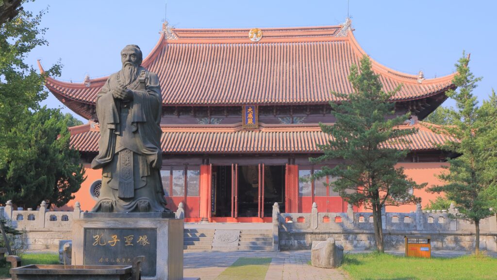 Ancient Chinese pagoda with a statue of Confucious in front. 