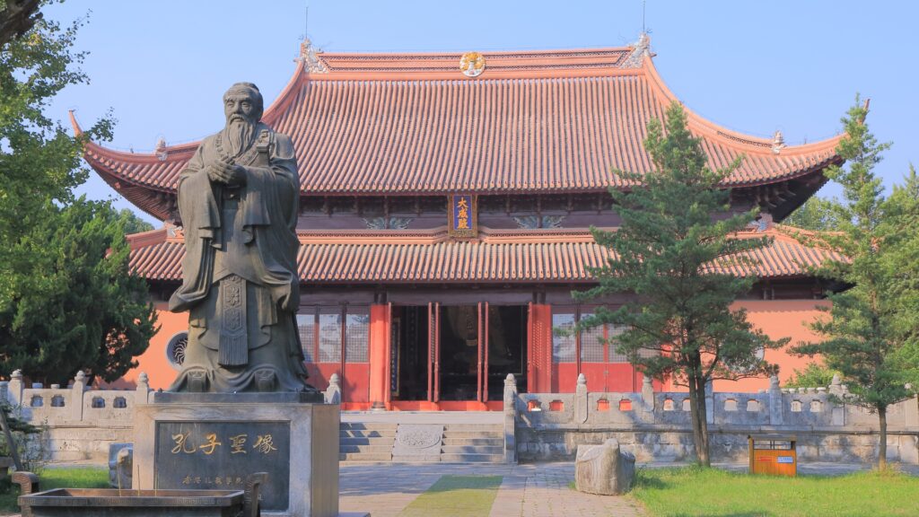Ancient Chinese pagoda with a statue of Confucious in front. is yoga a religion