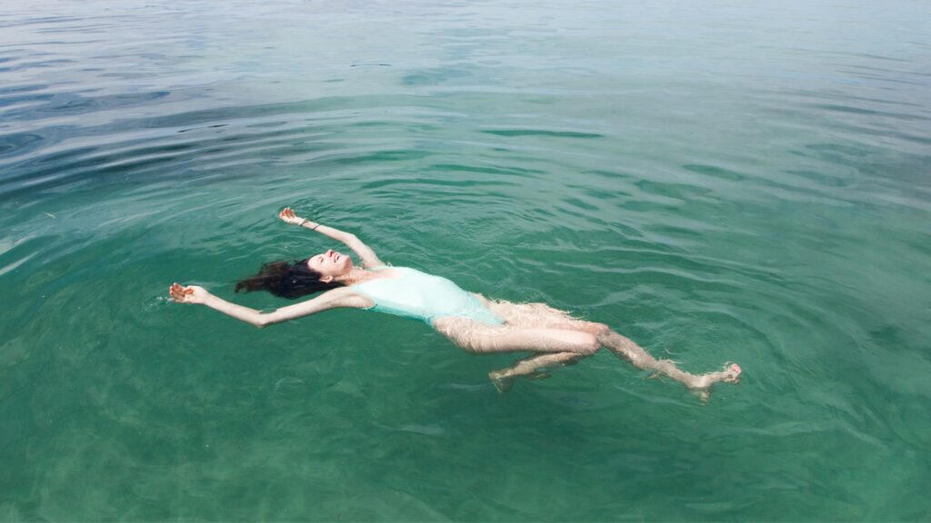 Woman floating in the turquoise blue ocean of Costa Rica. 