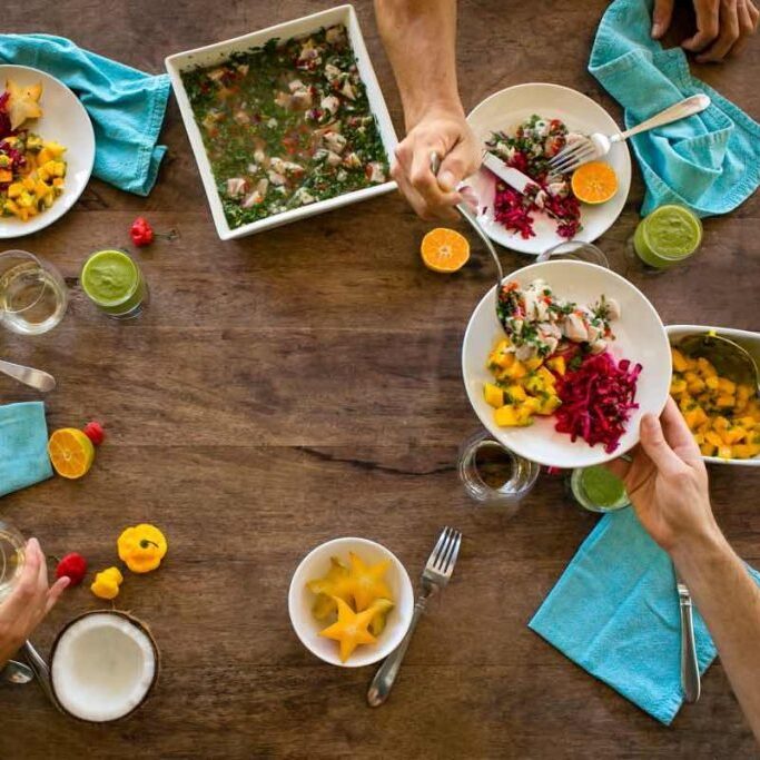Wooden table with lots of healthy, vibrantly colored dished meals.