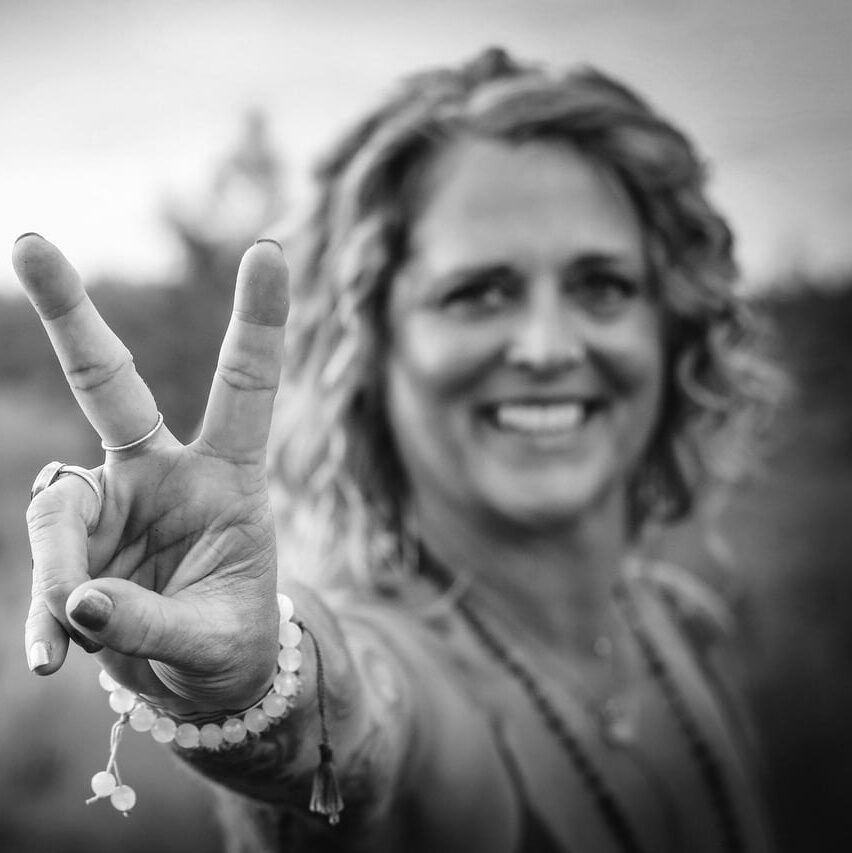 Black and white image of a woman smiling and holding out a peace sign in Costa Rica. 