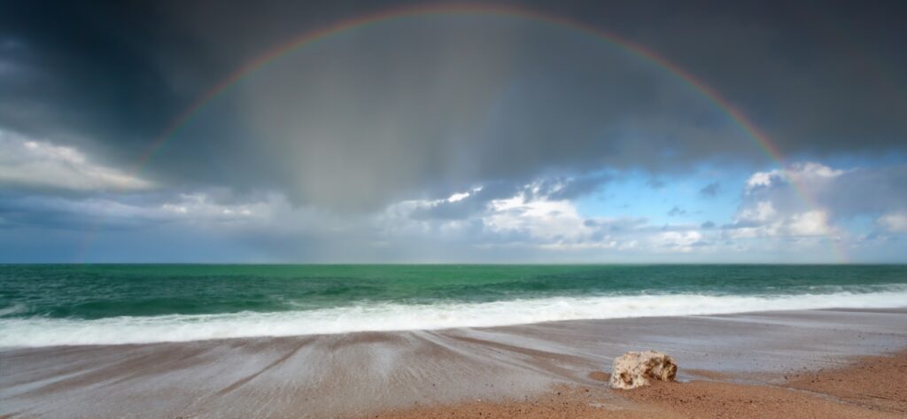Rainbow showing through dark storm clouds on the beach in Costa Rica.