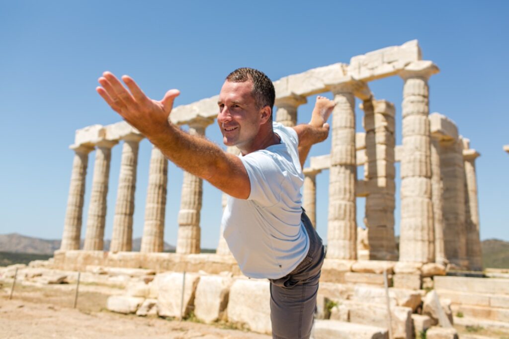 Yogi Aaron practicing dancer pose outside of ruins in Rome.