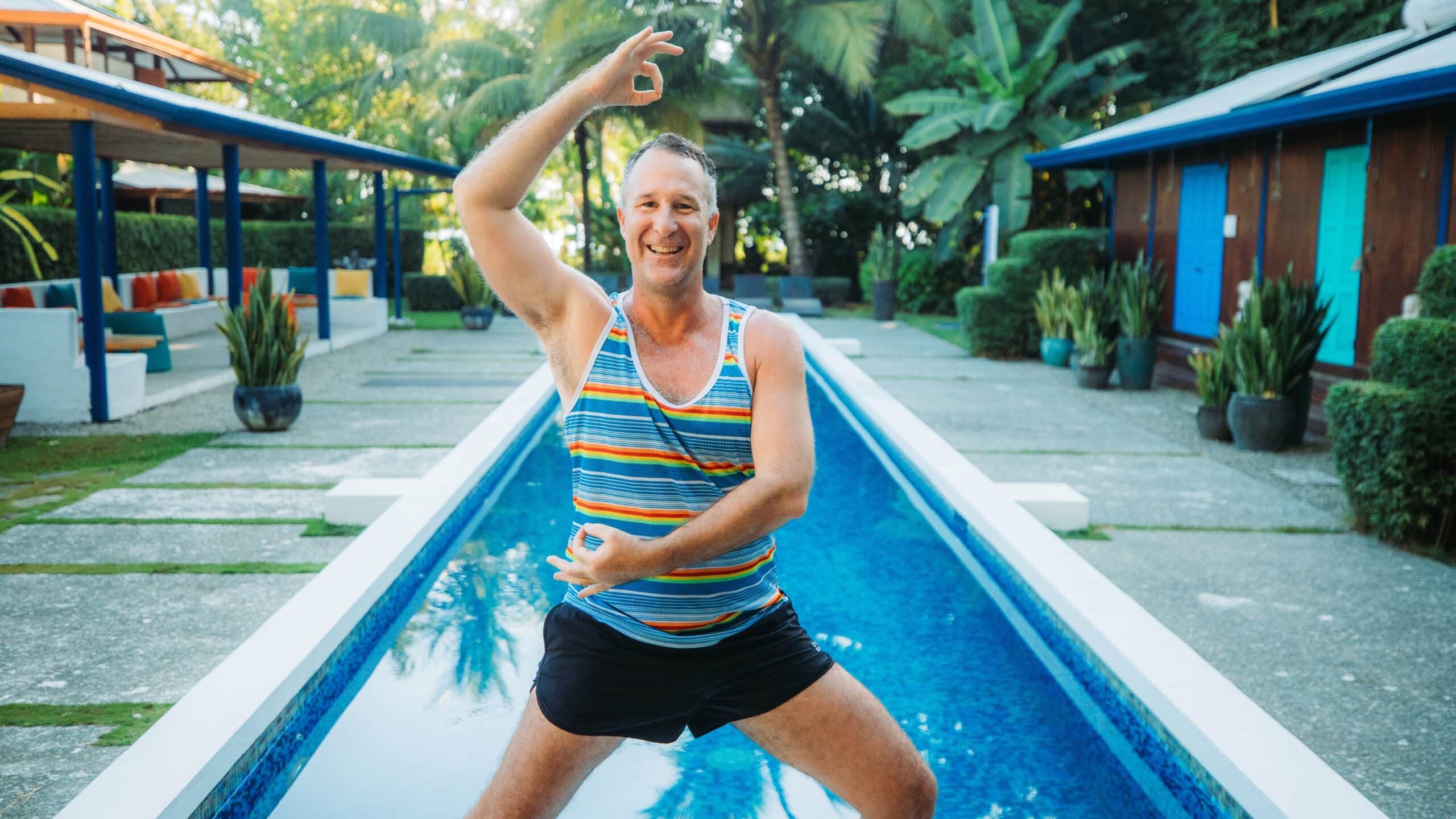 Yogi Aaron holding a side lunge and mudra pose in front of Blue Osa's chemical free lap pool in Costa Rica.
