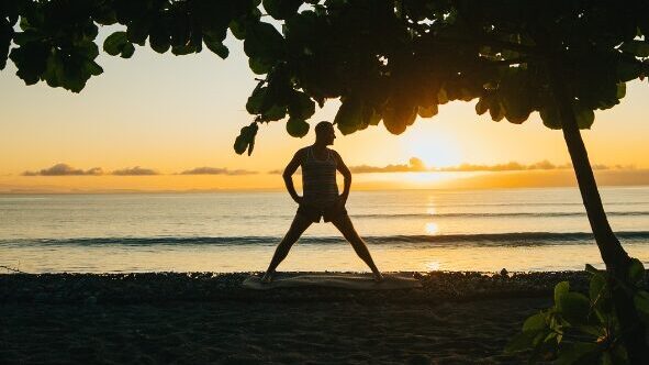 Silhoutte of Yogi Aaron in a wide legged standing position on the beach in front of Blue Osa in Costa Rica.