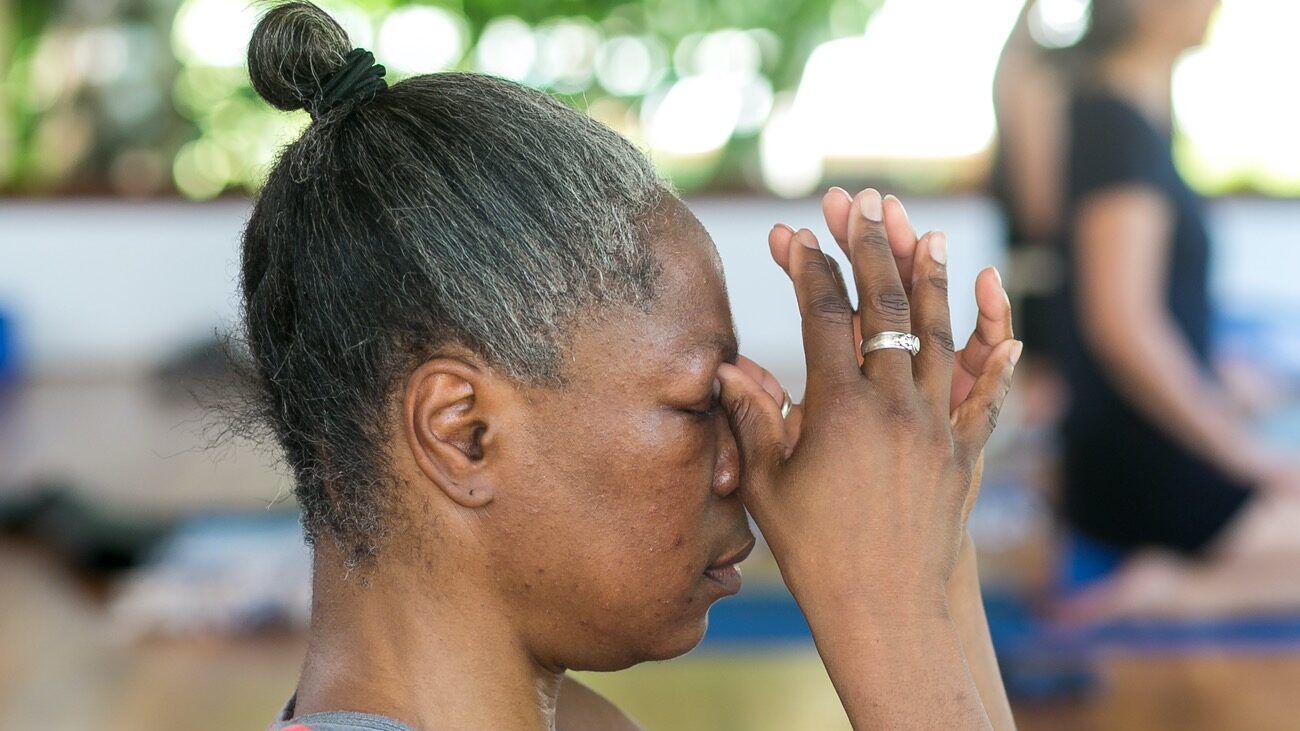 Woman meditating with her hands in prayer position by her third eye in Blue Osa's yoga shala in Costa Rica.