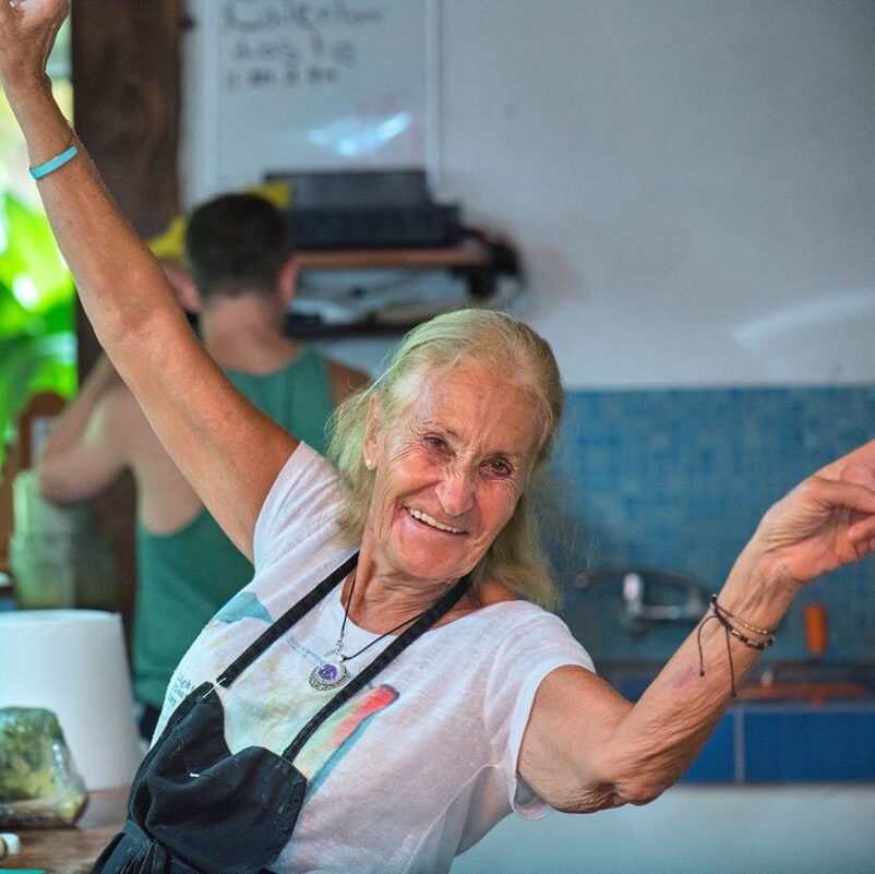 Chef Marie around 80 years old smiling while cooking in Blue Osa's kitchen in Costa Rica. 