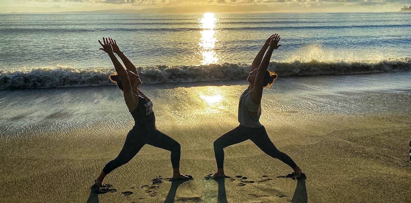 Christmas yoga retreat in Costa Rica at Blue Osa — two women practicing warrior pose on the beach at sunset