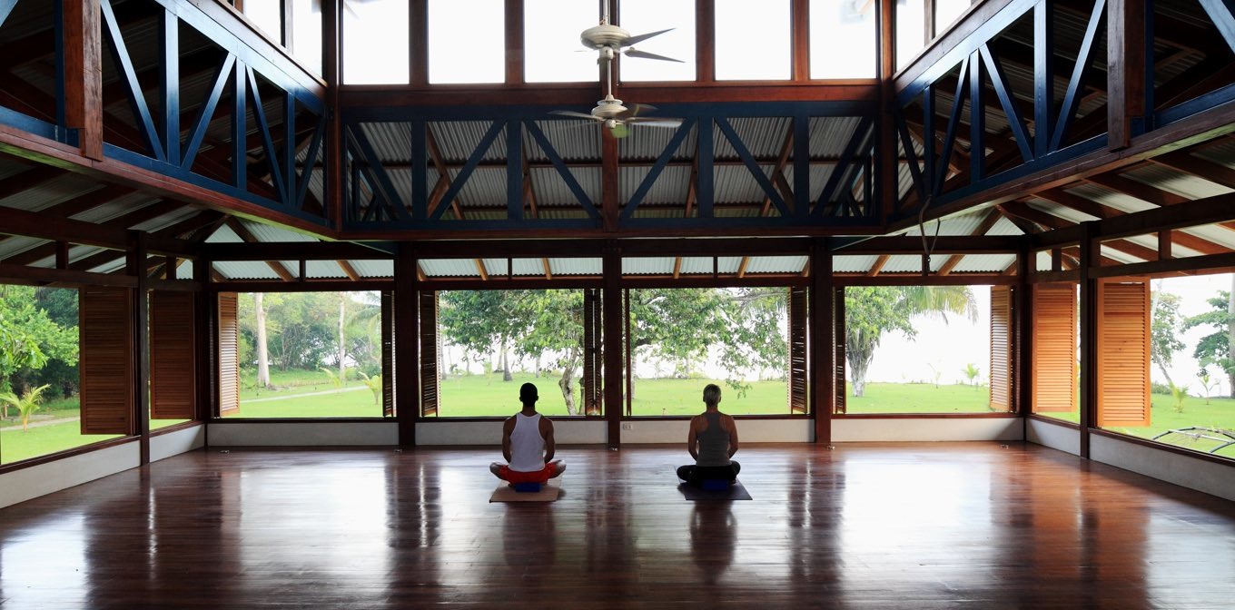 Solo yoga practitioner meditating in Blue Osa beachfront yoga shala during 300-hour yoga teacher training Costa Rica