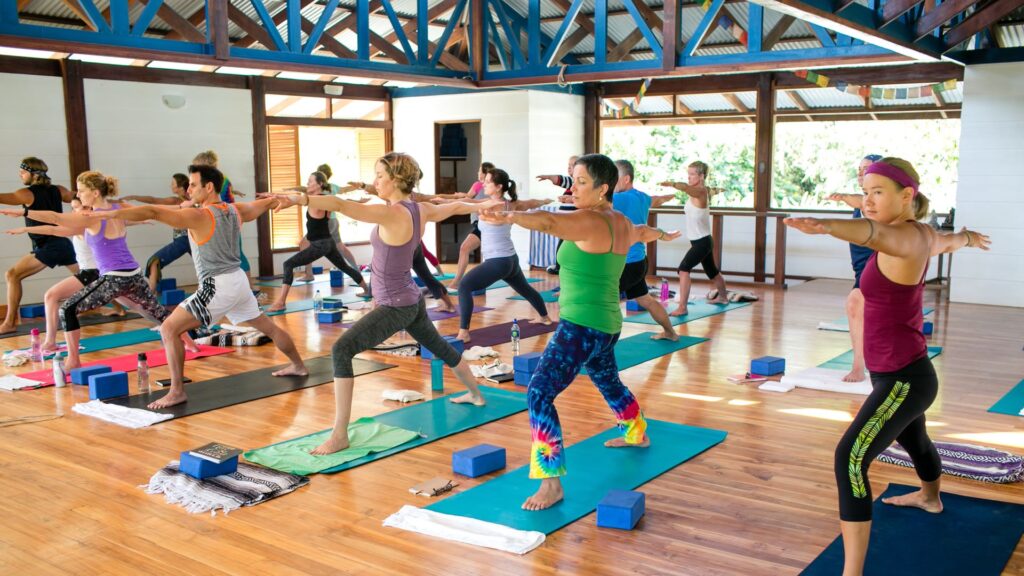 A full yoga class practicing warrior pose together in the open-air Blue Osa shala with jungle views in Costa Rica