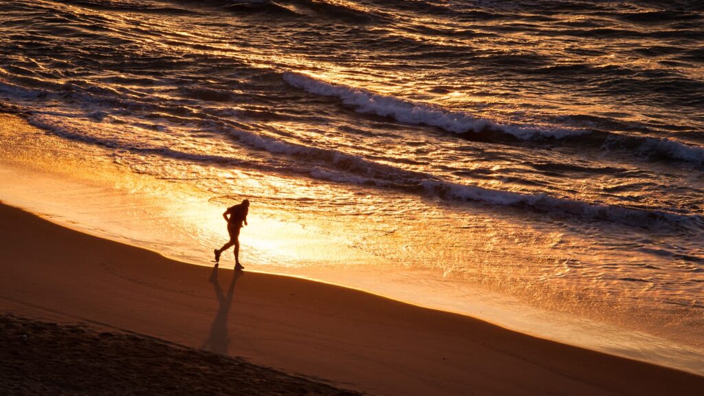 a person running on the osa along a beach at sunset