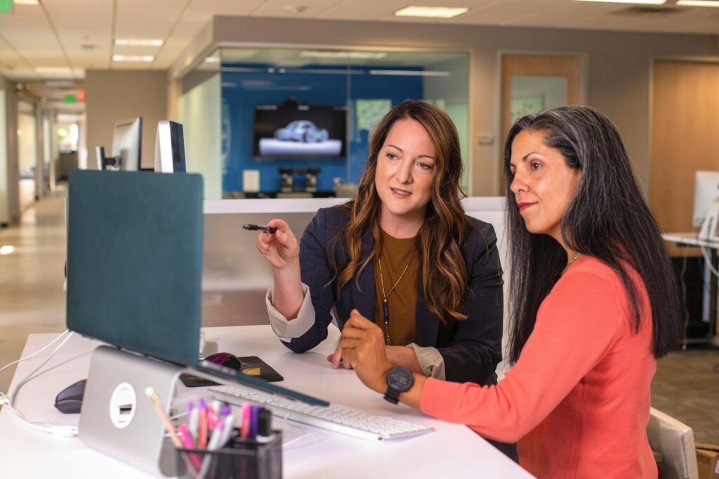 two women sitting at a table looking at a computer screen working vacation