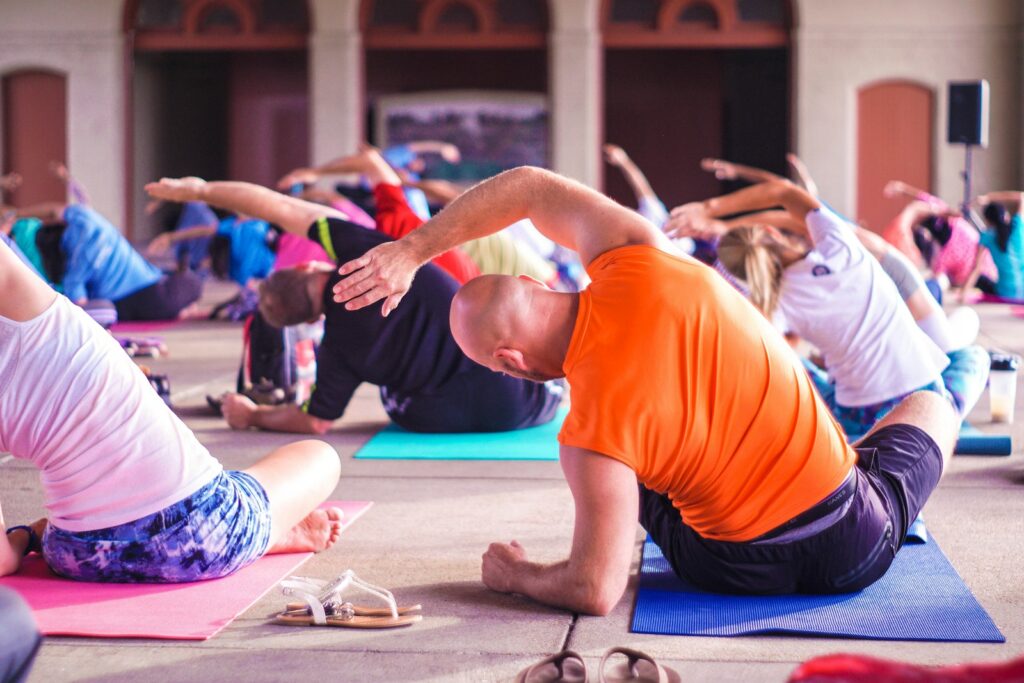 people exercising seated yoga pose hot yoga crowded yoga class wellness trend fitness