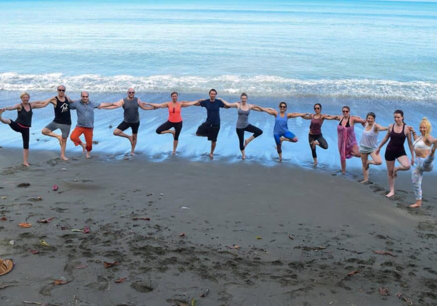 Group of yogis doing tree pose on the beach together facing the ocean during Blue Osa Yoga Retreat & Spa's Costa Rica Yoga Teacher Training Program