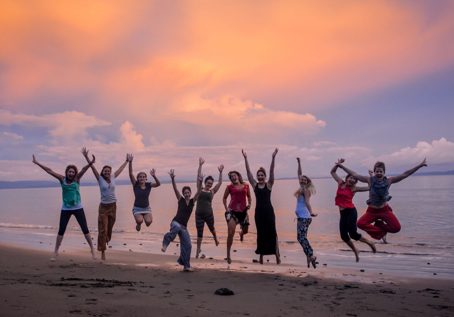 yoga students jumping for joy on the beach at Blue Osa Yoga Retreat & Spa in Costa Rica during a yoga teacher training program